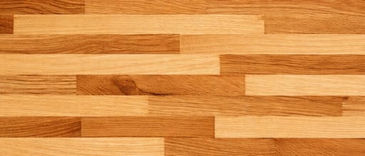 Close-up butcher block countertop surface pattern with natural oak wood grain, warm brown tones, and smooth laminated wood texture.