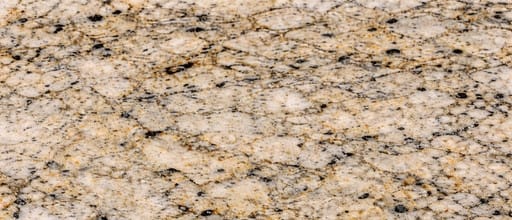 Close-up granite countertop surface pattern featuring white, beige, and gold natural stone texture with black mineral speckles, polished finish.