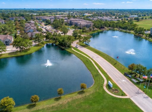Areas We Serve 6 Aerial view of Klein, Texas suburban neighborhood with twin lakes, fountains, curved roadway, green parks, and residential homes under clear blue sky.